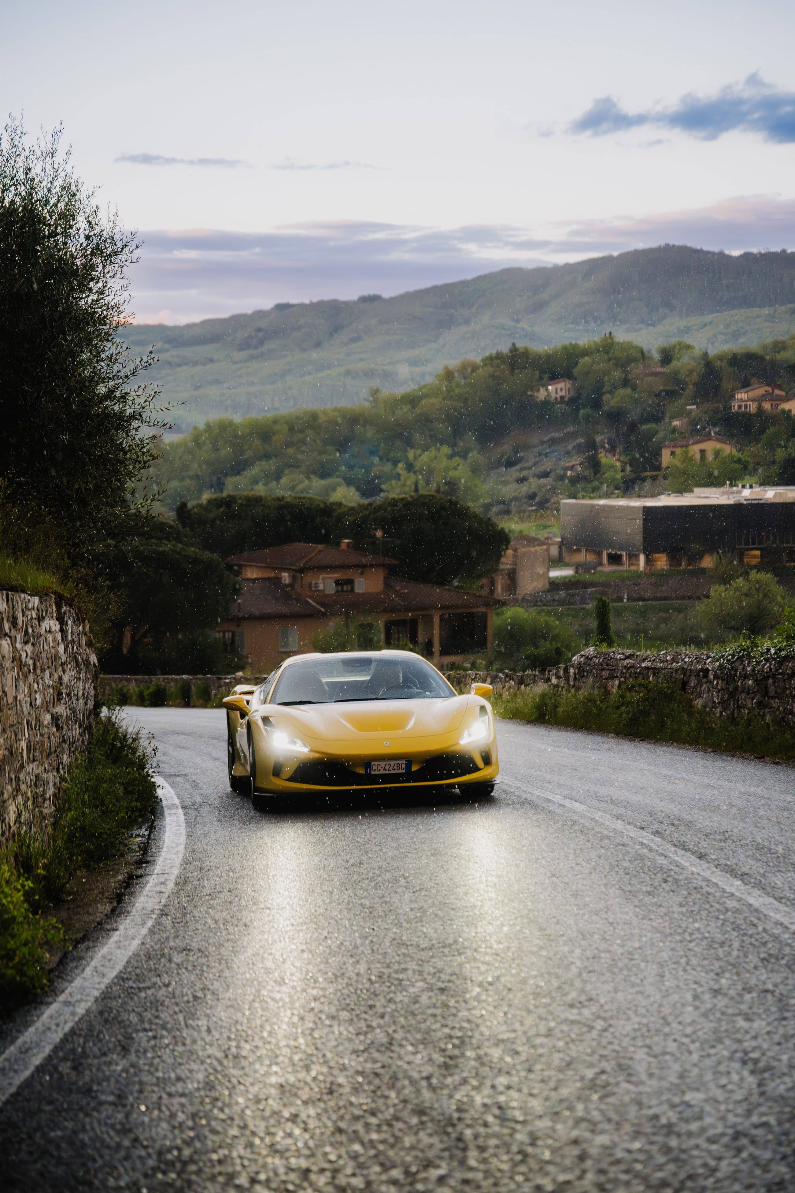 Supercar gialla su una strada bagnata fra le colline toscane al tramonto