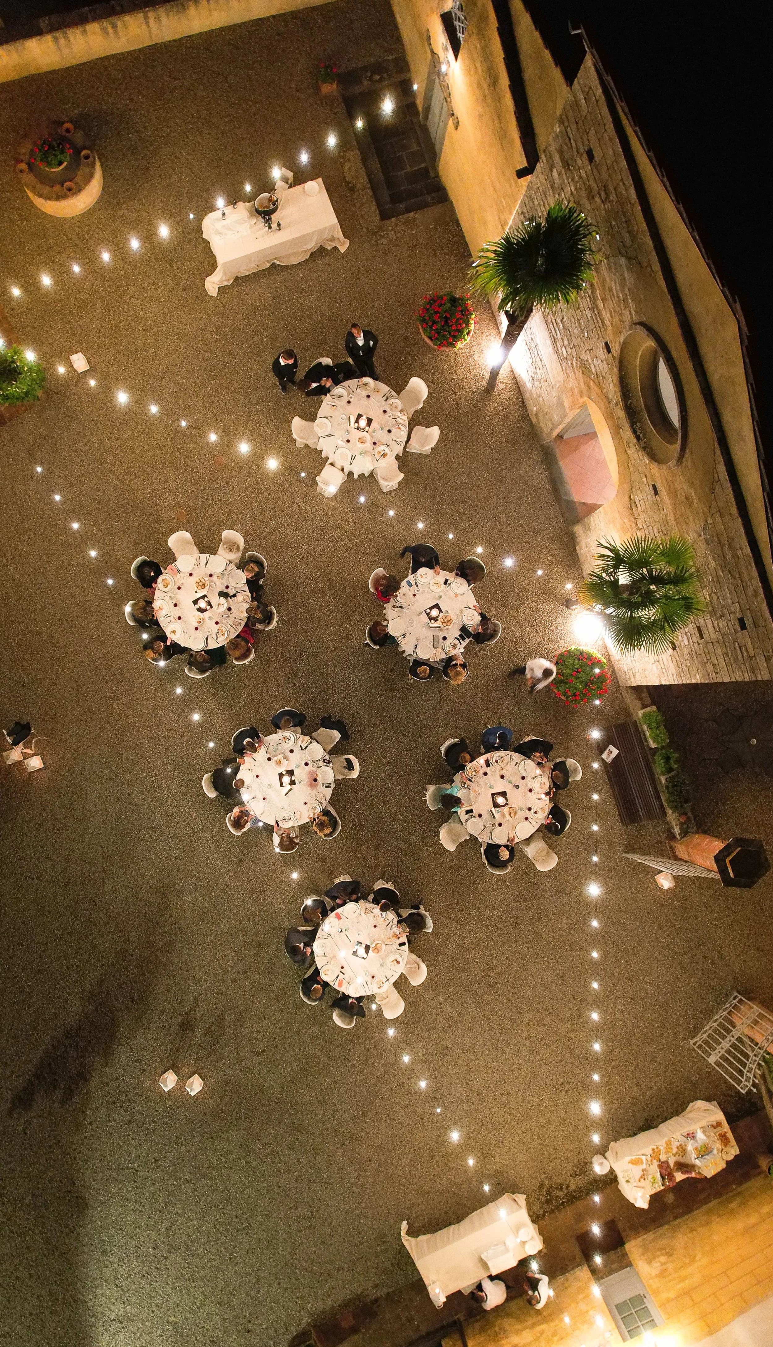Cena di gala con tavoli rotondi in una corte illuminata — evento su misura Rocca d'Italia