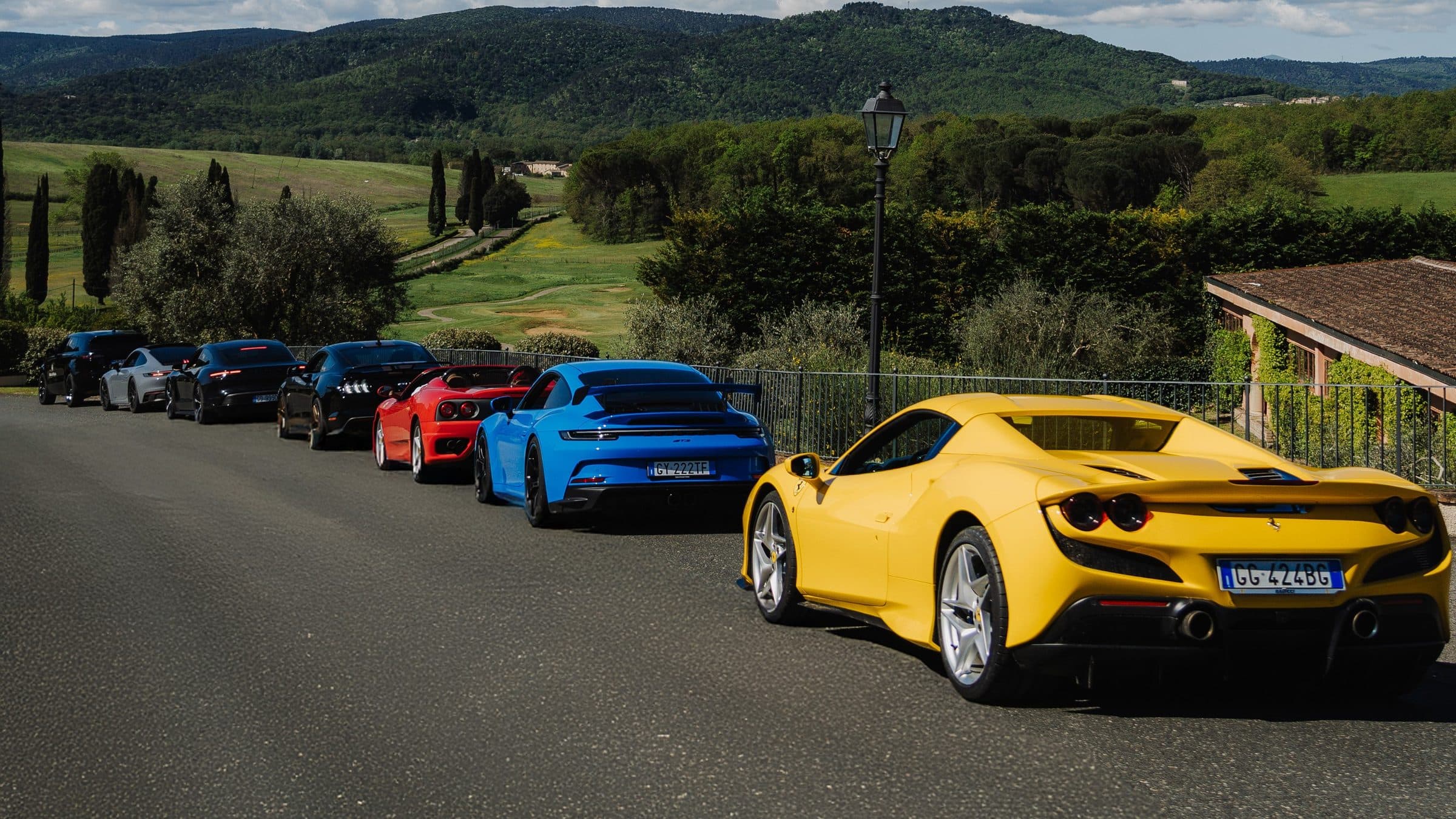Fila di supercar — Ferrari, Porsche e altre — con vista sulle colline toscane, esperienza Tuscany Hills di Rocca d'Italia