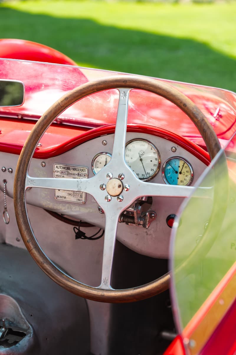 Dettaglio del volante in legno e della strumentazione di una Maserati d'epoca